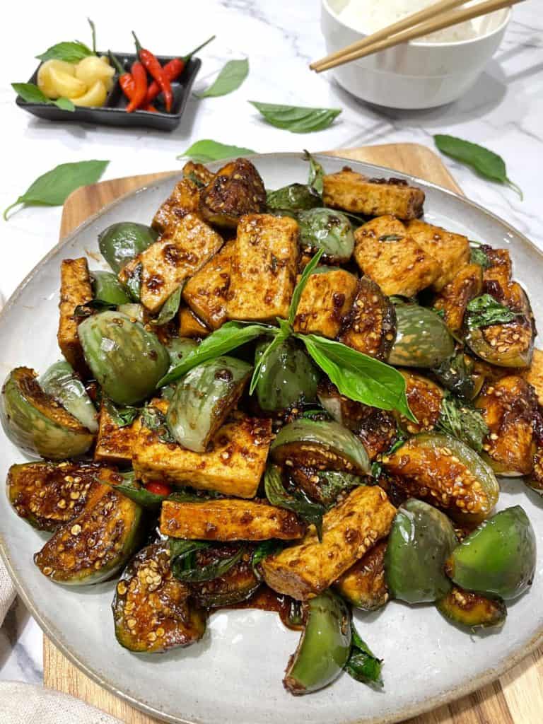 Thai tofu and eggplant stir fry with fresh basil on a gray plate