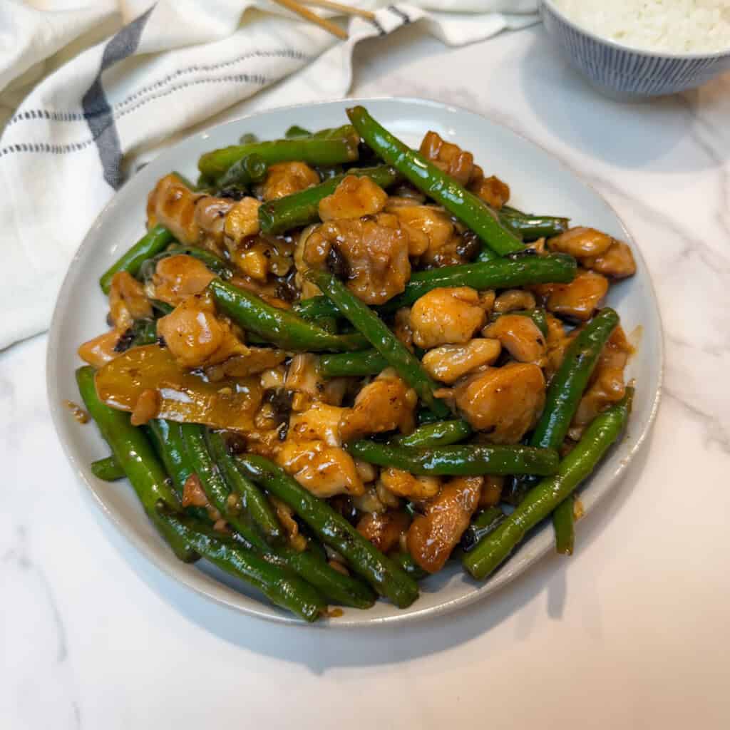 Chinese string bean chicken with green beans and tender chicken in a savory sauce on a white plate