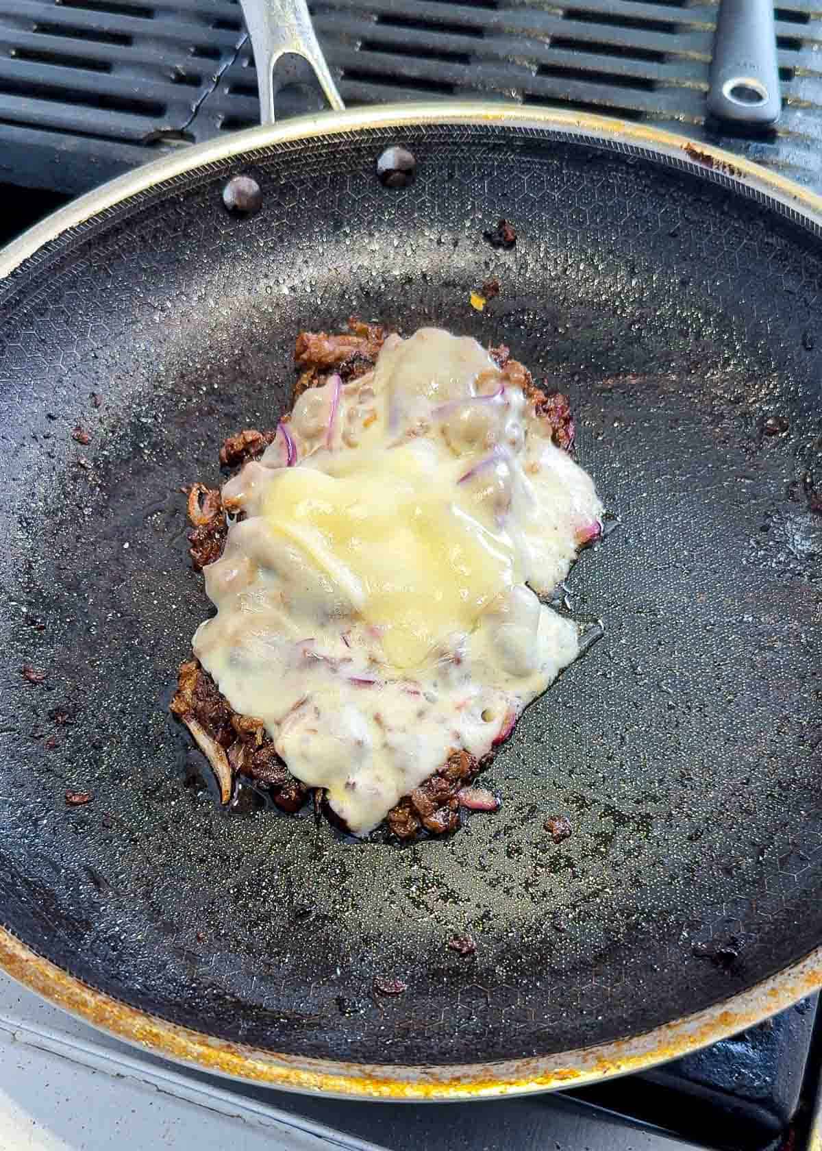Bulgogi cheese steak in a black pan with multi cheese on top.
