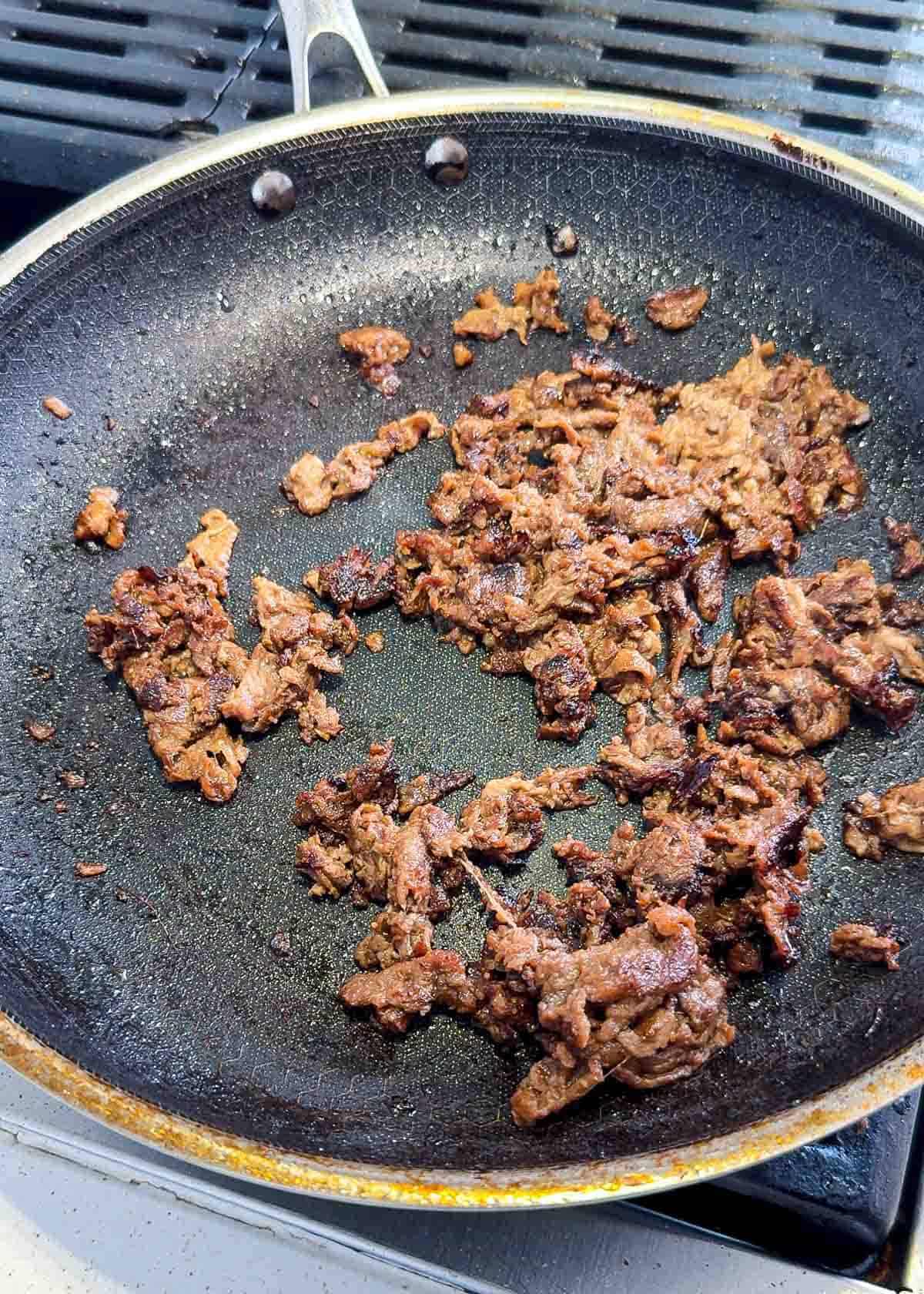 Grilled bulgogi beef for cheesesteak in a black pan with silver edges