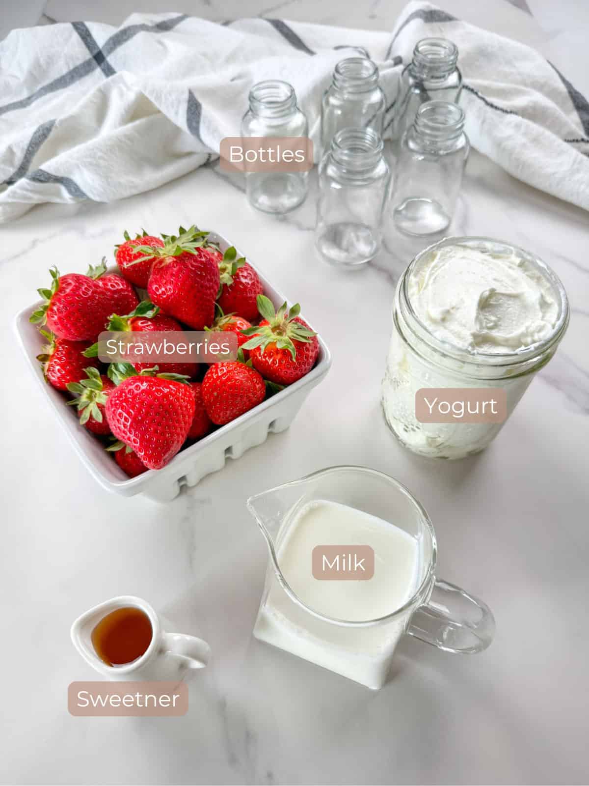 Labeled ingredients for Danimals yogurt strawberries in a container and milk and yogurt in glass containers