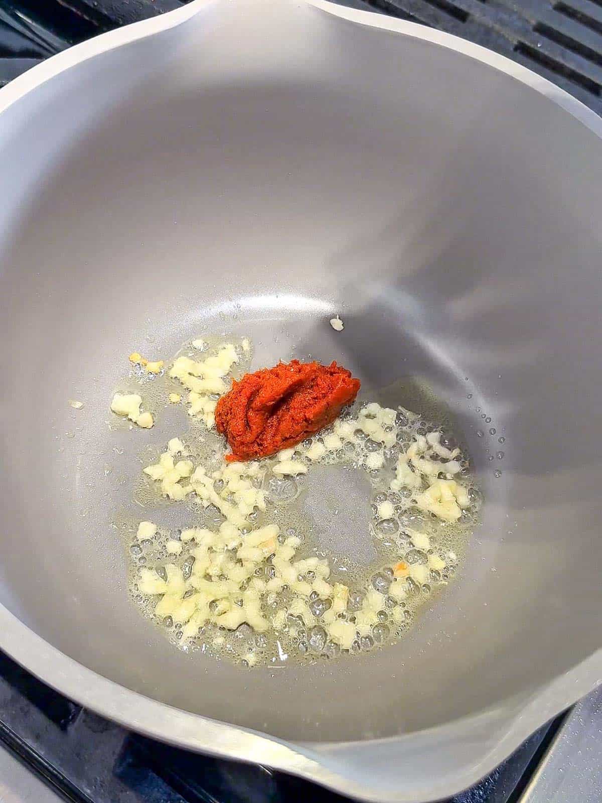 Garlic sautéing in a pot with oil for curry noodle soup