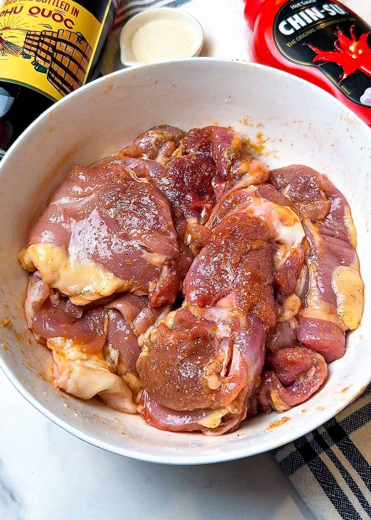 chicken thigh recipe marinade with fish sauce hot sauce and spices mixed with boneless chicken thighs