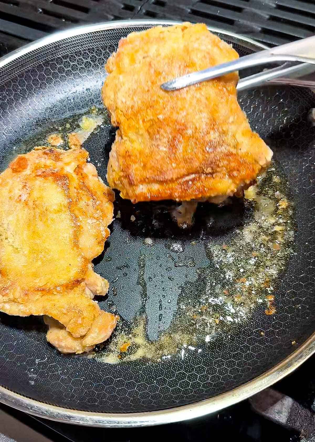 cornstarch coated chicken thigh pieces frying in oil until golden