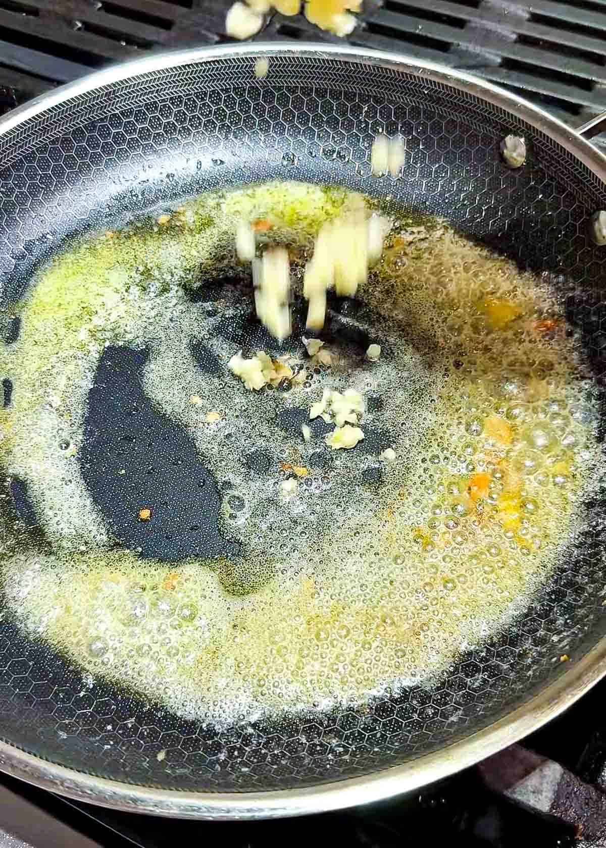 minced garlic cooking in butter in a pan for spicy glaze sauce