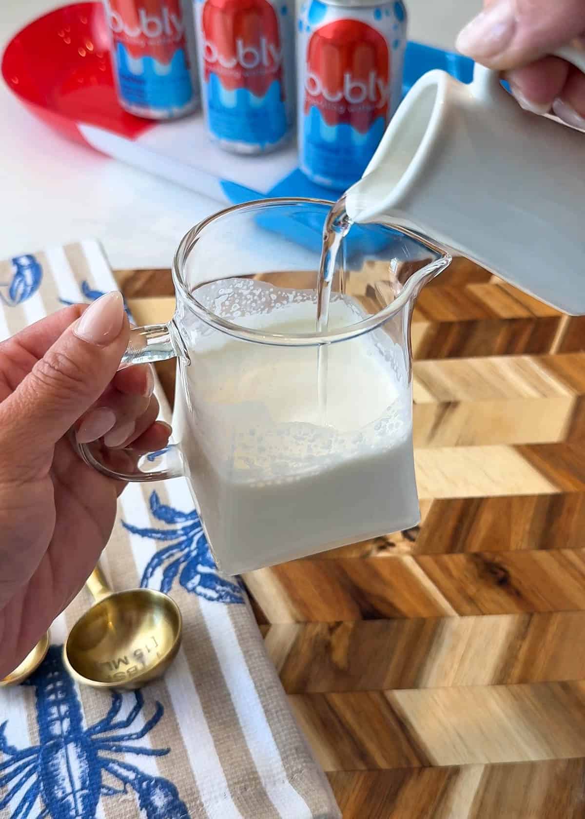 White liquid in a clear picture with a clear liquid being poured in with a summer themed background