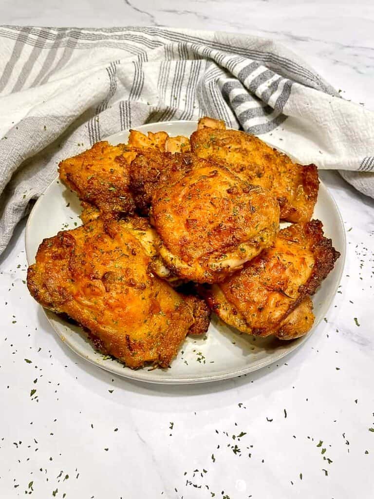 Juicy air fryer chicken thighs with golden crispy skin, garnished with parsley