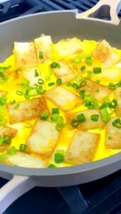 Finished bánh bột chiên with egg and green onions in a skillet