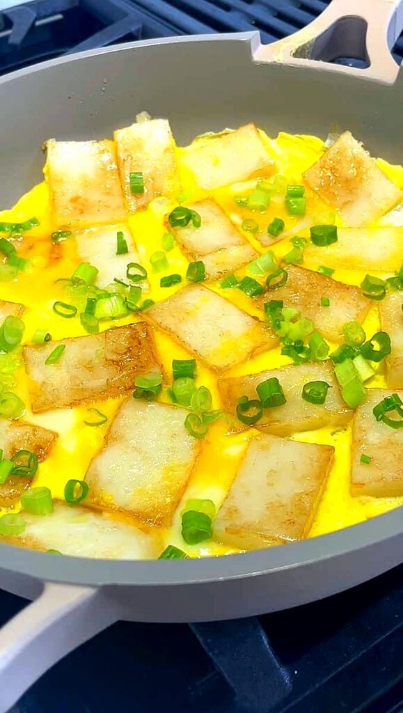 Finished bánh bột chiên with egg and green onions in a skillet