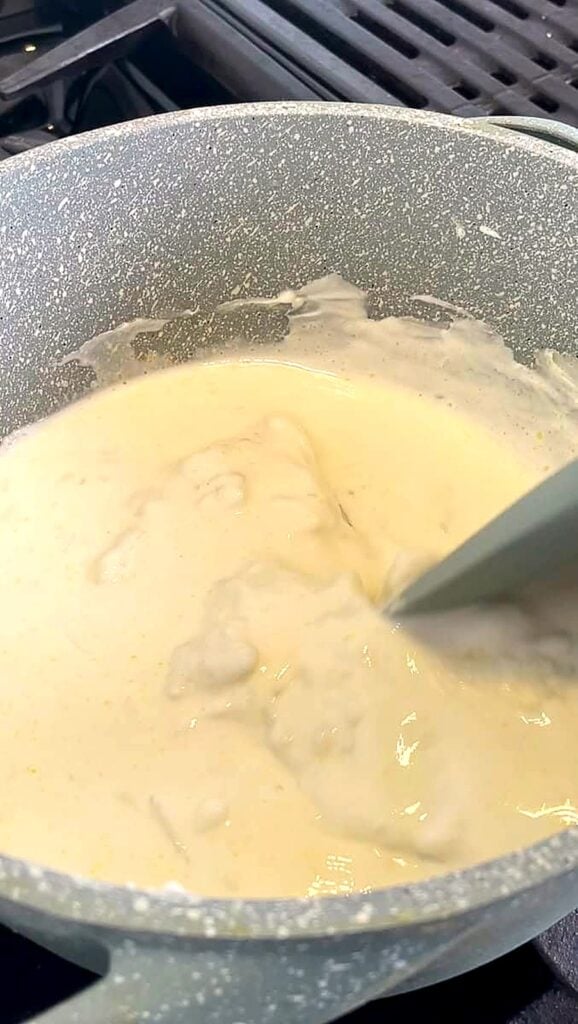 Whisking rice flour batter in a pan on the stove as it starts to thicken