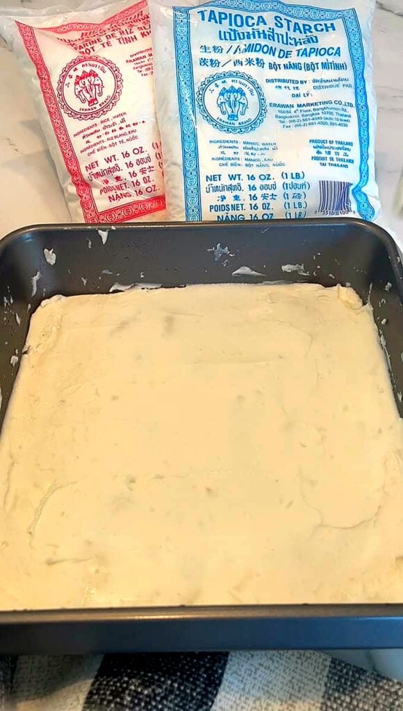 Rice flour batter pressed into an oiled square metal pan, ready to steam