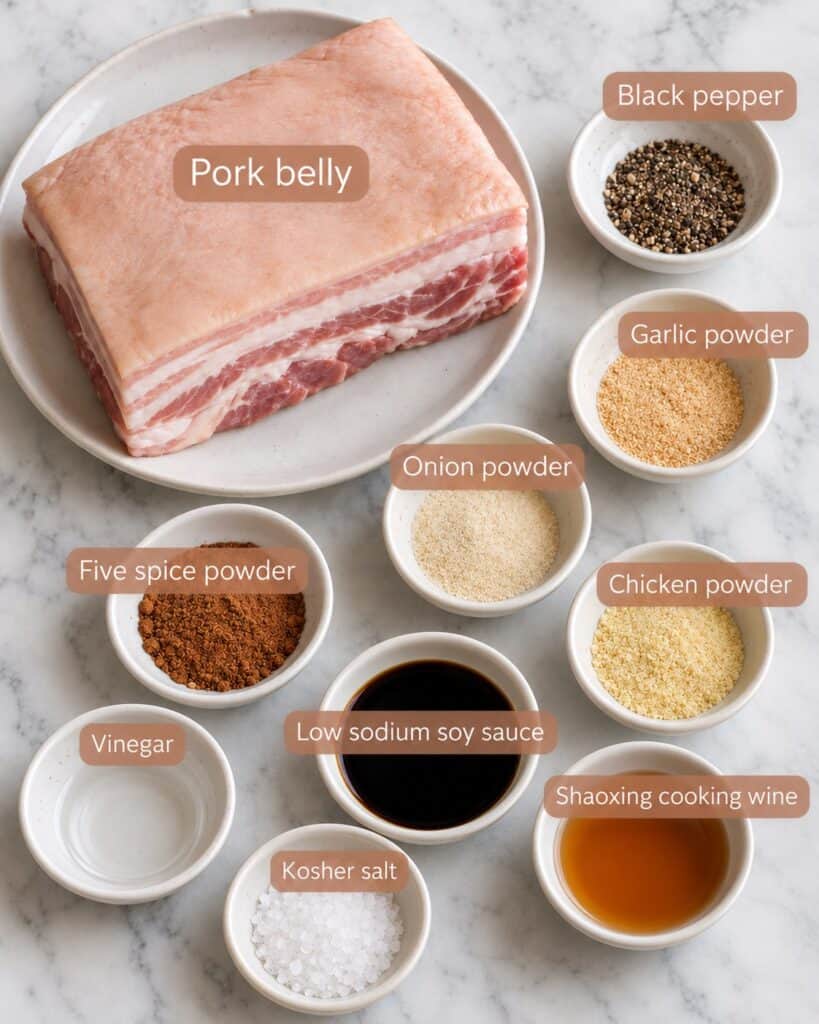 Ingredients for crispy Chinese roast pork belly: a slab of pork belly, black pepper, garlic powder, onion powder, five spice powder, chicken powder, low sodium soy sauce, Shaoxing cooking wine, vinegar and kosher salt
