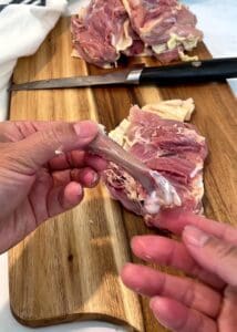 Chicken thigh bone held up next to the boneless skin-on chicken thigh it came from