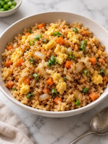 Hibachi fried rice with scrambled egg, carrots, onion and green onions in a white bowl