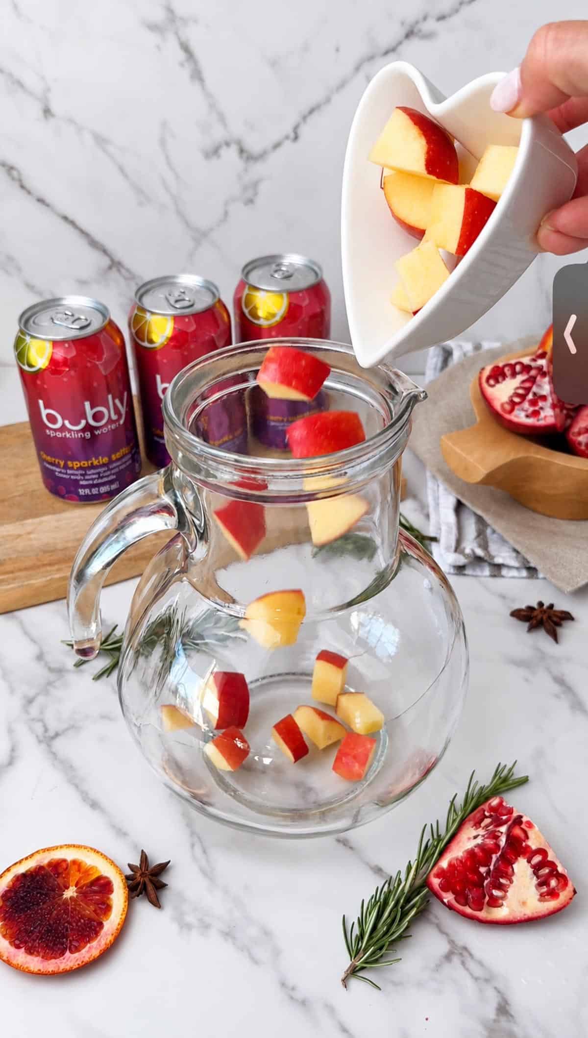 Ruby red sangria mocktail served over ice with fresh fruit and a rosemary garnish.
