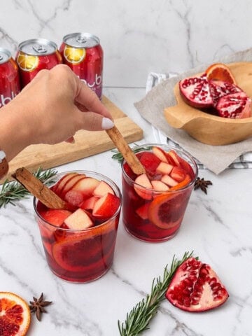 Adding a garnish to a fruit filled sangria mocktail.