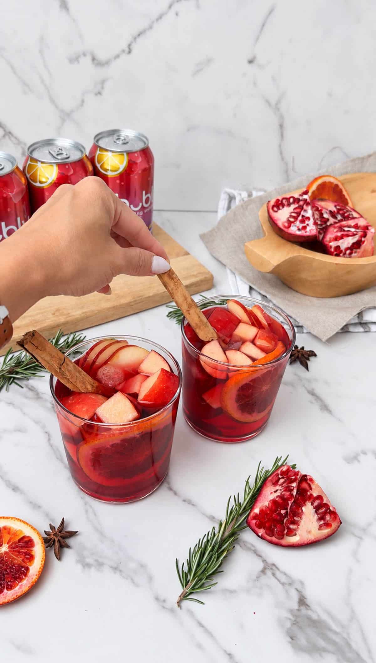 Adding a garnish to a fruit filled sangria mocktail.